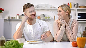 Smiling man looking with love at wife, thankful for tasty dinner, happy marriage