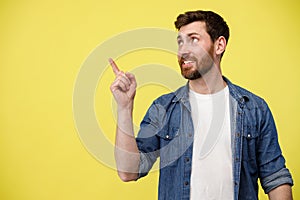Smiling man looking at side with raising his finger up and pointing to empty space
