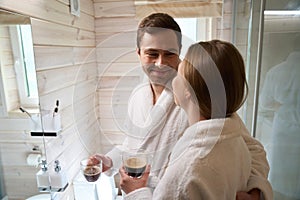 Smiling man looking at woman and holding coffee