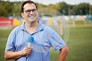 Smiling man with microphone is reporting from photo