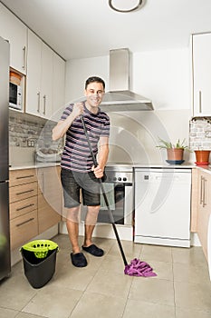 Smiling man mopping the kitchen floor