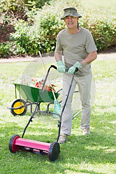 Smiling man mowing lawn