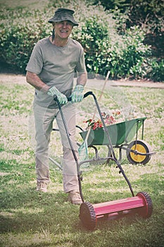 Smiling man mowing lawn