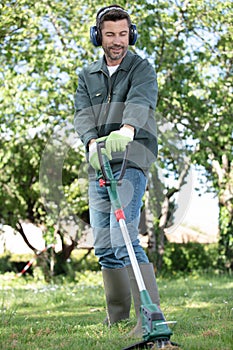 smiling man mowing lawn at home garden