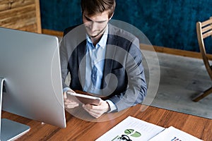 Smiling man in office working on digital tablet.