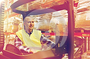 Smiling man operating forklift loader at warehouse