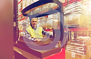 Smiling man operating forklift loader at warehouse