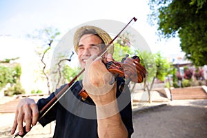 Smiling man outside playing violin