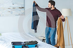 smiling man packing clothes into travel bag