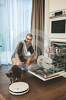 Smiling man petting his cat while houseworking