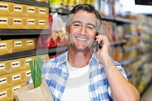 Smiling man on a phone call with grocery bag