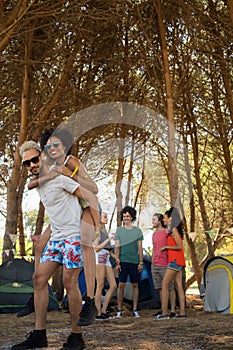 Smiling man piggybacking woman with friends in background