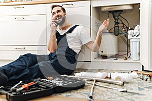 Smiling man plumber work in uniform talking by phone