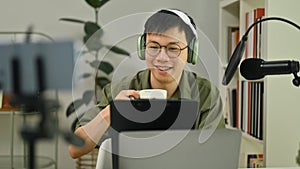 Smiling man radio host using condenser microphone for recording voice over radio interview guest conversation