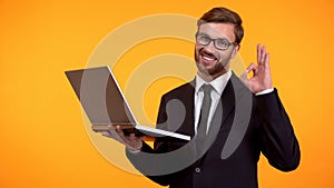 Smiling man reading e-mail and showing ok sign, winking at camera, promotion