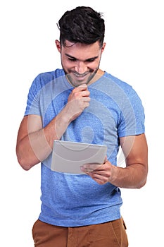 Smiling man is reading interesting stuff on his tablet pad