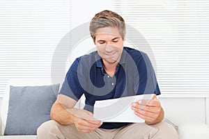 Smiling Man Reading Letter At Home