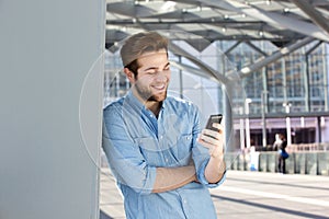 Smiling man reading text message on mobile phone