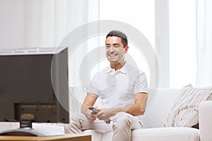 Smiling man with remote control watching tv
