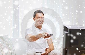 Smiling man with remote control watching tv