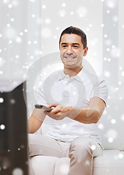 Smiling man with remote control watching tv