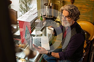 Smiling man responding to his messages in a cafe.