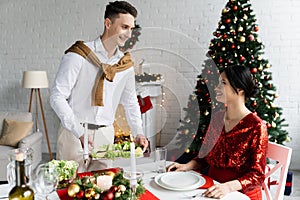 smiling man serving meal near pregnant