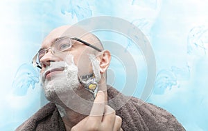 Smiling man shaving his beard by razor blade