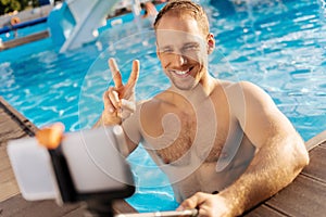 Smiling man showing a V sign while taking selfie