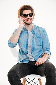 Smiling man sitting on chair and talking by cell phone