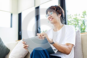 Smiling man sitting on couch at home using laptop for remote working from home office in living room