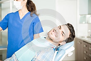 Smiling Man Sitting By Dentist At Clinic