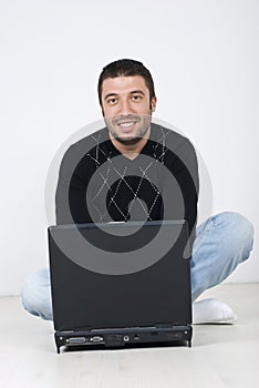 Smiling man sitting on floor with a laptop