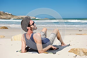 Smiling man sitting on secluded beach