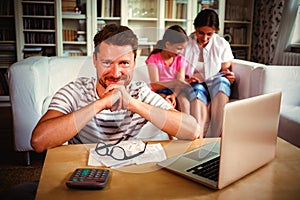 Smiling man sitting at table with bills and laptop