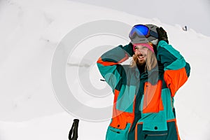 smiling man skier in bright colorful ski suit against background of snow