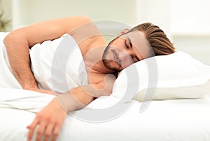 Smiling man sleeping on a comfortable bed.