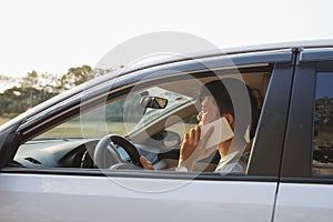Smiling Man Speak on Smart Phone in White Car. The businessman successful driving his car and speaking on the cellphone