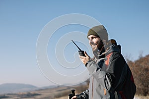 Smiling man speaking on two-way radio for hiking