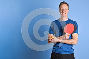 Smiling man in sportswear with ping-pong equipment blue isolated background