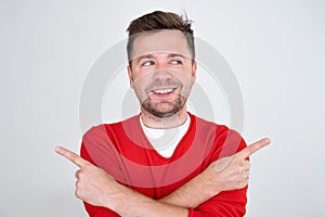 Smiling man standing with crossed hands and pointing to copy space on both sides