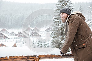 Smiling man standing and enjoying snowy weather on winter resort