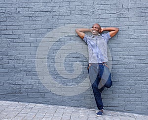 Smiling man standing with his hands behind head