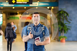Smiling man standing at modern airport departure terminal holding passport and boarding pass