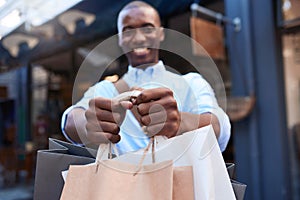 Smiling man standing outside carrying a load of shopping bags