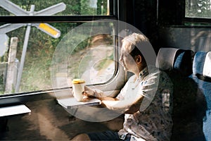 A smiling man in a suburban train looking out the train window