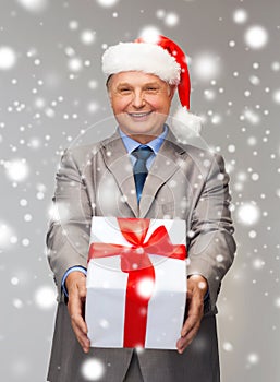 Smiling man in suit and santa helper hat with gift