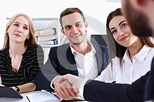 Smiling man in suit shake hands as hello in office