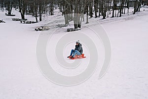 Smiling man in sunglasses going down hill on sled