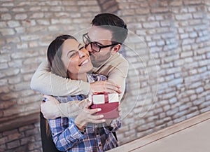 Smiling man surprises his girlfriend with present at home